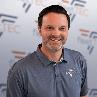 Smiling man in a Fleet TEC polo shirt stands against a branded backdrop.