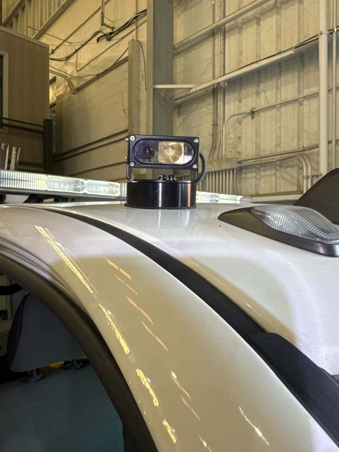 Mounted camera on a vehicle roof inside a garage, showcasing advanced fleet technology.